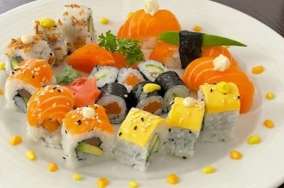 Assortiment de sushis et makis variés avec garnitures colorées, présenté sur une assiette blanche.