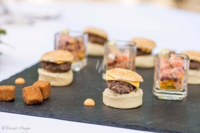 Traiteur Traiteur Benoit Bruley Épagny #5 Mini-burgers, verrines de tartare et cubes panés disposés sur une ardoise noire, présentés pour un apéritif.