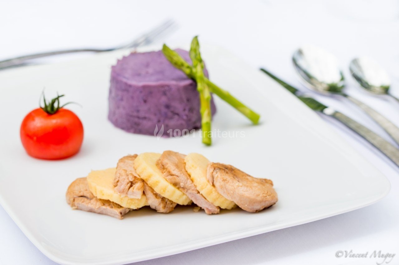 Traiteur Traiteur Benoit Bruley Épagny #1 Assiette avec magret de canard tranché, purée violette, asperges vertes et tomate cerise, servie sur une table dressée.