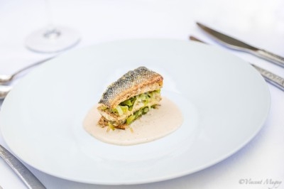 Traiteur Traiteur Benoit Bruley Épagny #2 Filet de poisson grillé sur un lit de légumes, nappé de sauce blanche, servi dans une assiette blanche.