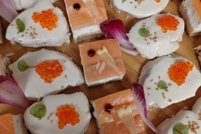 Assortiment de bouchées apéritives avec saumon fumé, œufs de poisson, crème et décorations florales.