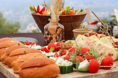 Traiteur Traiteur D'azur Saint-Vallier-de-Thiey #2 Plateau de buffet avec pains garnis, légumes frais, tomates cerises, fromage et desserts en arrière-plan.