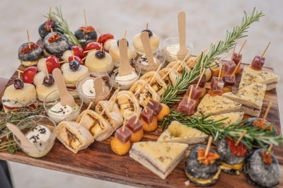 Traiteur Traiteur D'azur Saint-Vallier-de-Thiey #3 Plateau en bois garni de bouchées variées, incluant mini-sandwichs, verrines, fromages et décorations de romarin.