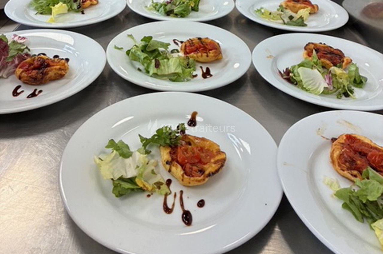 Assiettes contenant des tartelettes aux légumes et des salades vertes, disposées sur une table en inox.