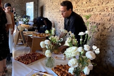 Un traiteur prépare un buffet avec des fleurs blanches en décoration dans une salle en pierre.