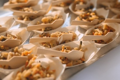 Portions individuelles de salade de pâtes servies dans des coupelles en bois avec des fourchettes assorties.