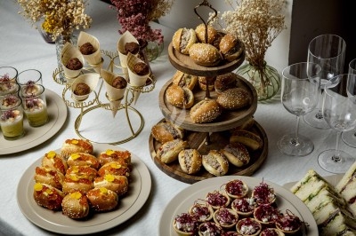 Buffet avec mini-sandwichs, verrines, toasts garnis et fleurs séchées en décoration sur une nappe blanche.