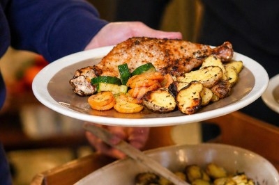 Assiette contenant une cuisse de poulet grillée, des rondelles de carottes, de courgettes et des pommes de terre rôties.