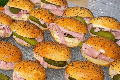 Petits sandwichs au jambon, cornichons et beurre, servis dans des pains garnis de graines de pavot.
