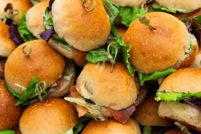 Traiteur Montagu Troyes #2 Plateau de mini-burgers garnis de salade et de charcuterie, présentés sur un support en bois.