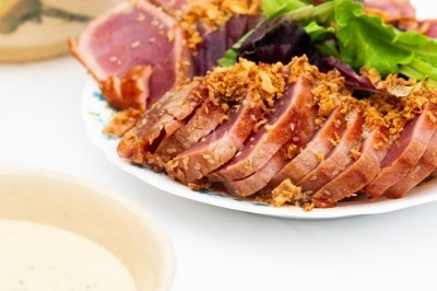 Traiteur Montagu Troyes #4 Assiette de tranches de thon mi-cuit garnies de feuilles vertes et d'oignons frits, accompagnée de sauces.