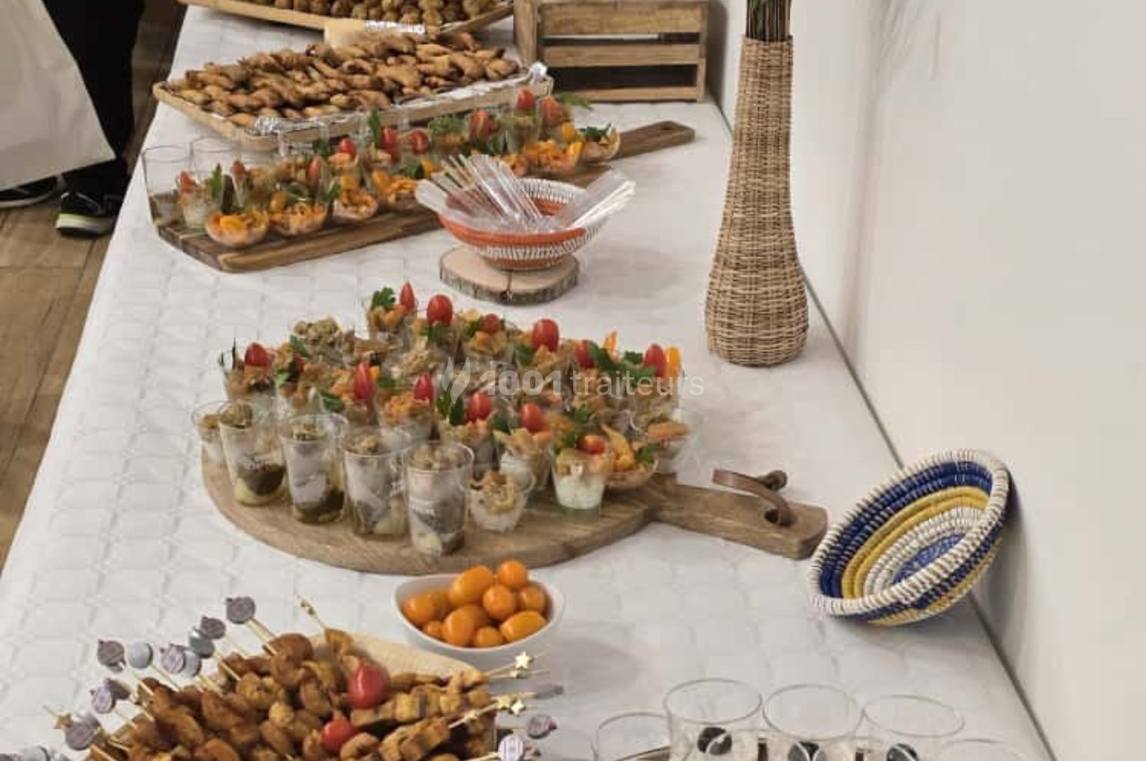 Buffet avec verrines, brochettes, fruits et autres amuse-bouches disposés sur une table blanche.