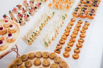 Plateau de bouchées apéritives variées disposées sur des supports, comprenant canapés, tartelettes et amuse-bouches colorés.