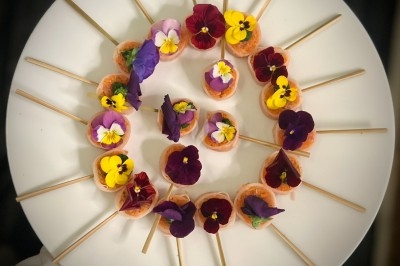 Traiteur Romain Merlet Traiteur Bussy-Saint-Georges #3 Assortiment de bouchées colorées décorées de fleurs comestibles, disposées en cercle sur une assiette blanche.