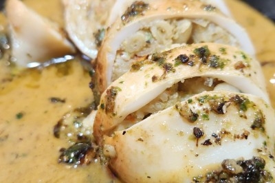 Traiteur Les Very Traiteur Marseille 11 #3 Calamar farci servi dans une sauce crémeuse aux herbes, présenté dans une assiette noire.