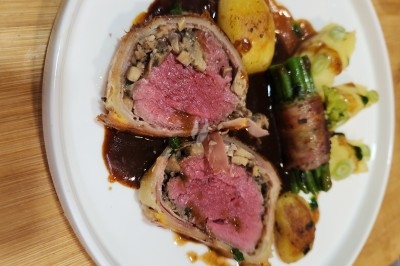 Traiteur Les Very Traiteur Marseille 11 #4 Plat de bœuf Wellington tranché, accompagné de pommes de terre, haricots verts enroulés de lard et sauce brune.