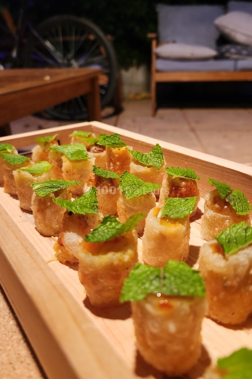 Traiteur Les Very Traiteur Marseille 11 #1 Assortiment de bouchées croustillantes garnies, décorées de feuilles de menthe, présentées sur un plateau en bois.