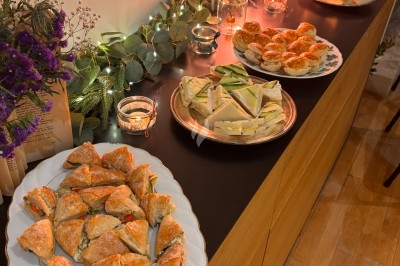 Assortiment de plats salés disposés sur un buffet en bois, décoré de guirlandes lumineuses et de fleurs.