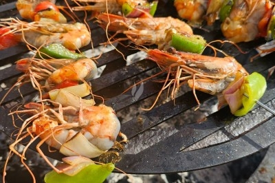 Crevettes et légumes colorés grillés sur une grille de barbecue en plein air.
