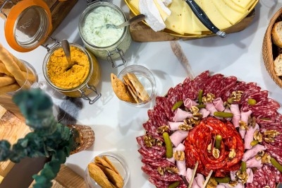 Plateau de charcuterie et fromages variés avec condiments, pain et crackers sur une table de buffet.