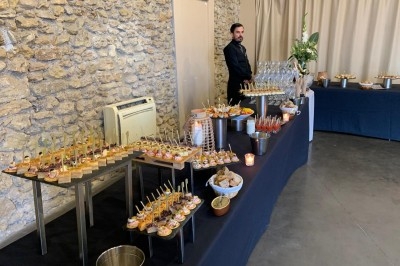 Traiteur Les Sens du Lez Saint-Jean-de-Védas #3 Buffet de réception avec amuse-bouches variés, verres et décor sobre dans une salle aux murs en pierre.