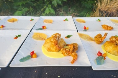 Assiettes dressées avec croustillants de crevettes, sauce jaune, légumes décoratifs et feuilles imprimées.