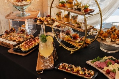 Traiteur La Table Confidentielle Gacé #2 Table dressée avec des bouchées apéritives variées, cocktail et présentoir circulaire, dans un cadre élégant.