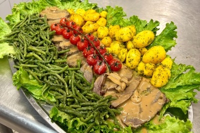 Boeuf en Tranche, sauce au Poivre Plateau garni de rôti en sauce, haricots verts, pommes de terre persillées, tomates cerises et feuilles de salade.