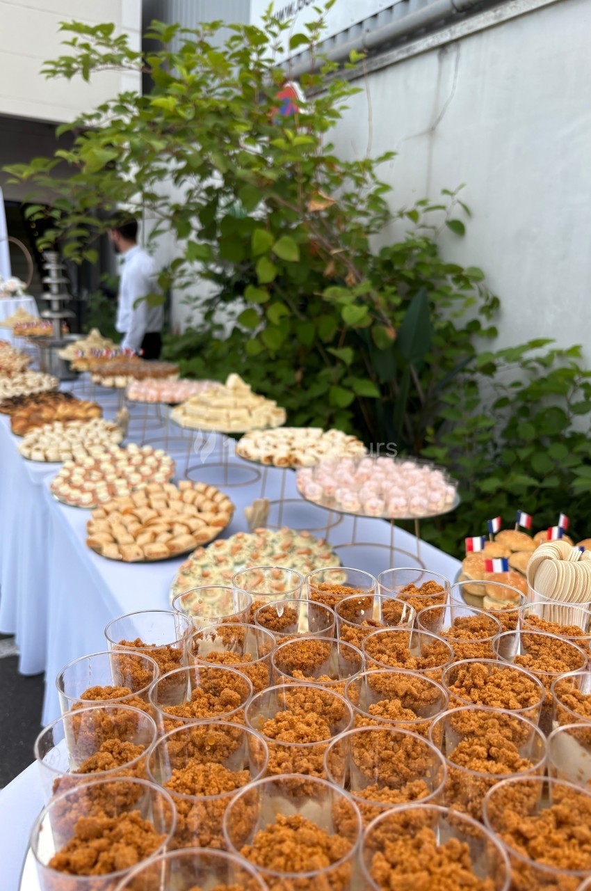 Buffet Buffet en extérieur avec une variété de desserts et amuse-bouches disposés sur plusieurs tables alignées.